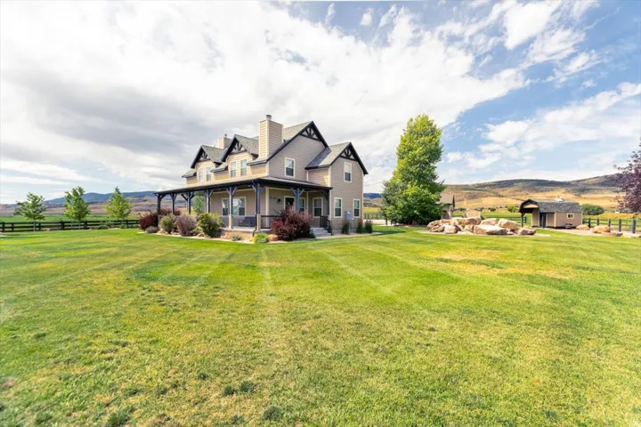 Two-story residence with a covered front porch featuring decorative columns, dormer windows, and a chimney stack