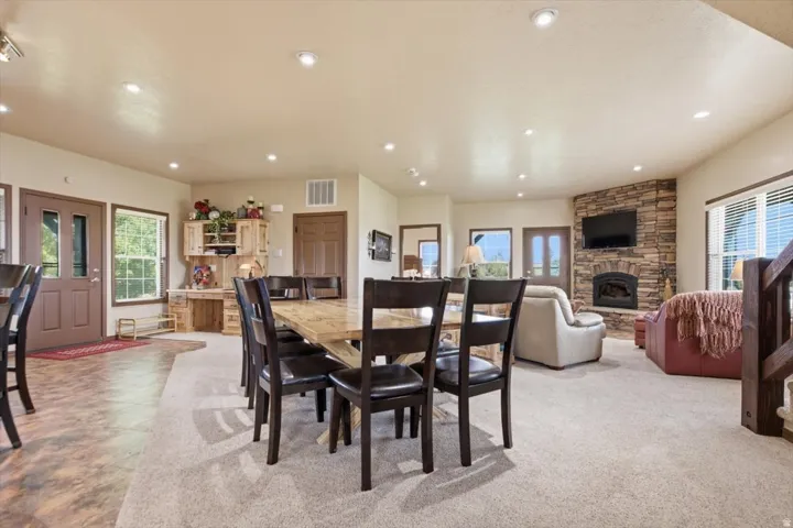 Recessed lighting illuminates the open-concept living space with a stone-clad fireplace and wood-finish flooring