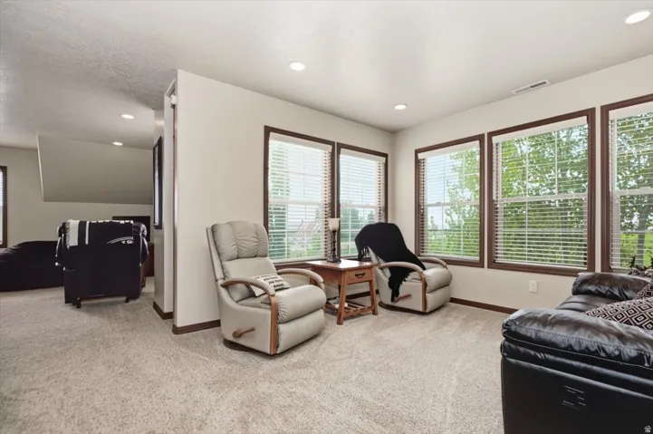 Multiple windows with wood trim, recessed lighting, and light-toned carpet flooring