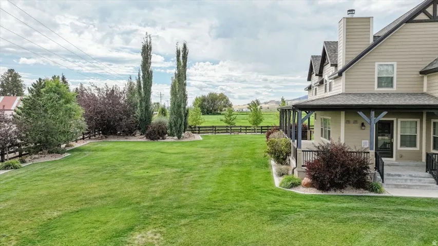 Expansive lawn, covered porch with dark wood posts, exterior siding, and a dark shingle roof