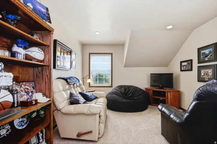 Carpeted flooring with sloped ceiling, recessed lighting, and a built-in bookshelf