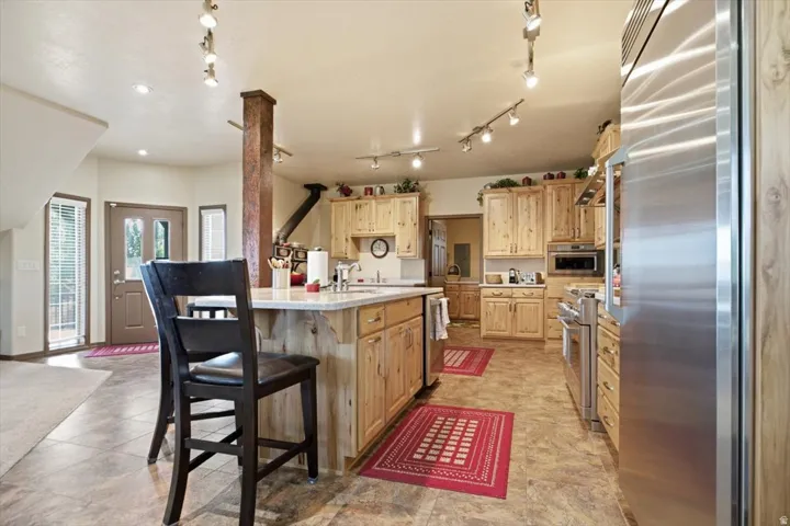 Kitchen featuring light wood cabinetry, a central island with a light-toned countertop, stainless steel appliances, and track lighting