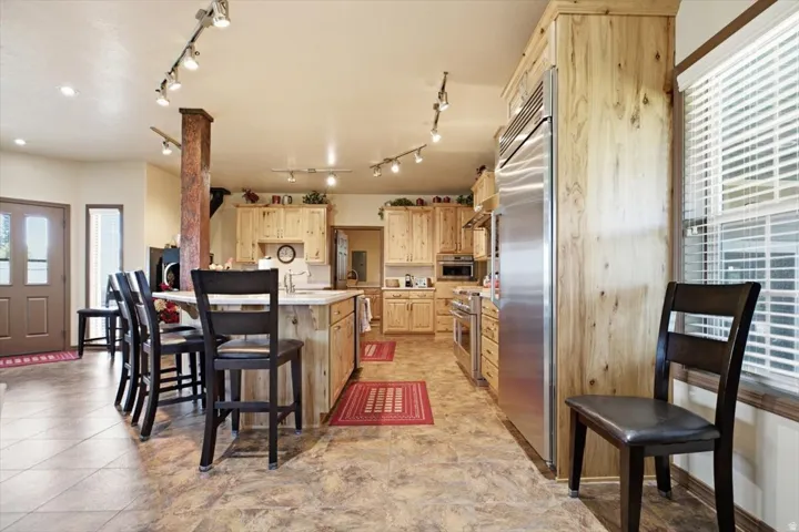 Open-concept kitchen featuring wood-finish cabinetry, stainless steel appliances, a center island with seating, and track lighting