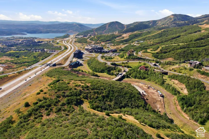 Mountainous terrain featuring natural vegetation, a body of water, and an adjacent highway