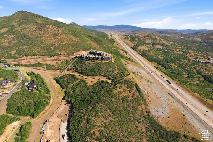 Elevated properties nestled into mountainous terrain, featuring distant highway access