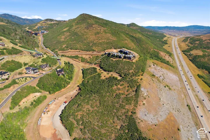 Mountainous terrain with natural vegetation, winding roads, and residential structures