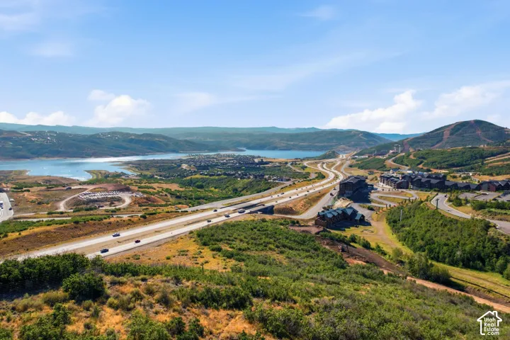 Expansive mountain landscape with a prominent body of water, multi-lane highway, and clustered residential buildings