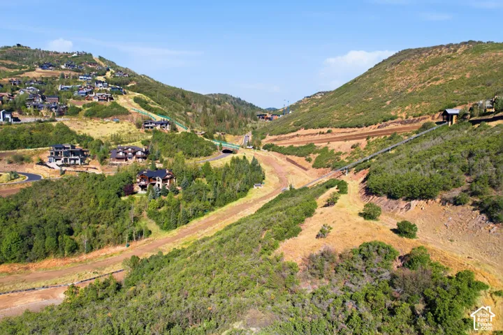 Hillside properties featuring diverse architectural styles, surrounded by natural mountainous terrain and established trees