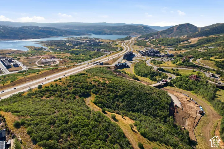 Expansive landscape featuring diverse terrain, a prominent body of water, and surrounding mountains