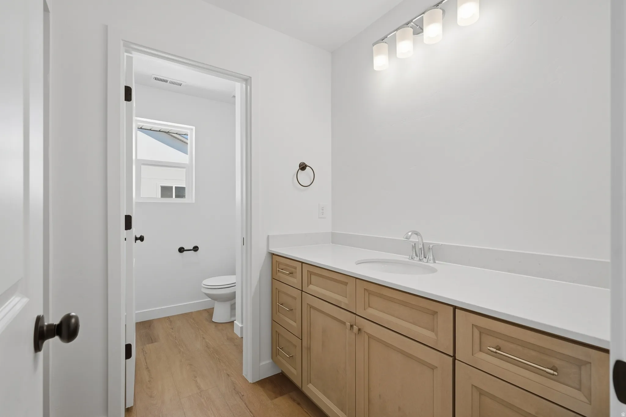 Extended vanity with a built-in sink, light wood-finish cabinetry, and a light-toned countertop