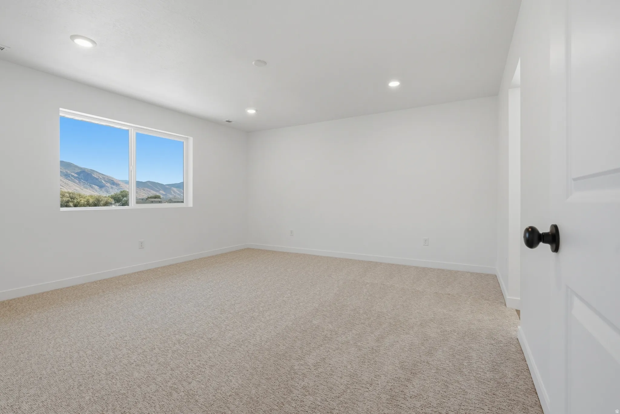 Neutral wall finishes, recessed ceiling lights, and light-toned carpet flooring