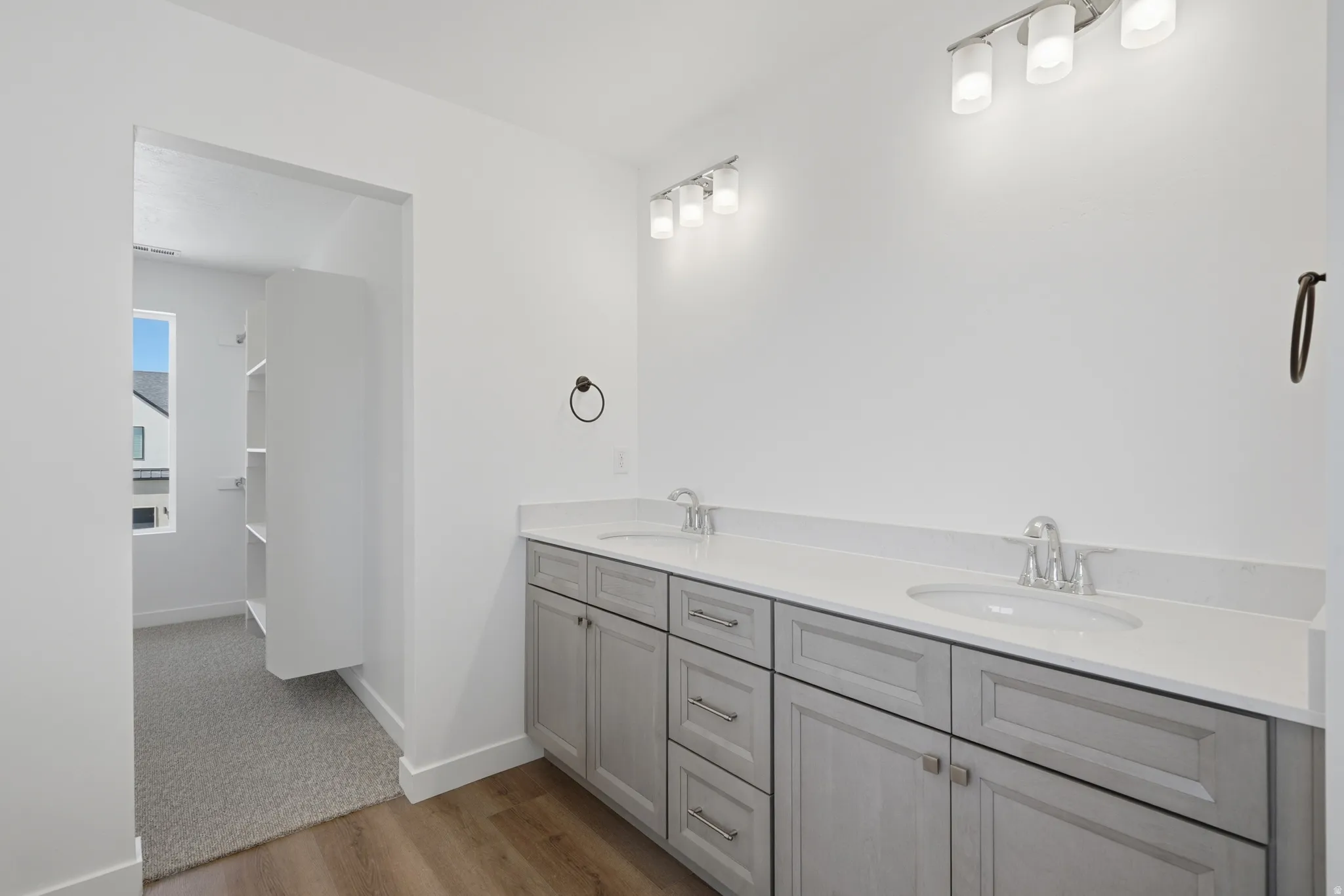 Dual vanity with light gray cabinetry, white countertops, and chrome fixtures