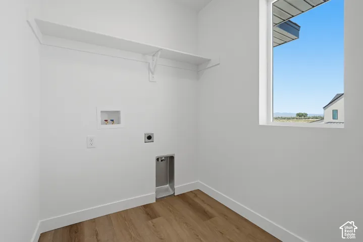 Dedicated laundry space featuring a window, built-in shelving, wood-finish flooring, and white trim