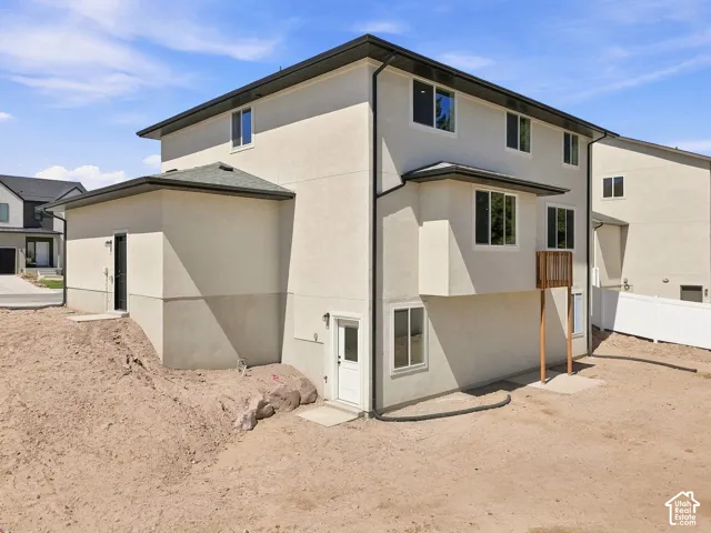 Two-story stucco exterior with multiple windows, featuring a lower-level entry door and a second-story deck structure