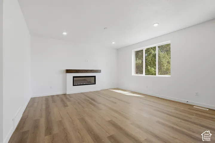 Recessed lighting, wood-finish flooring, and a modern fireplace with a wood mantel