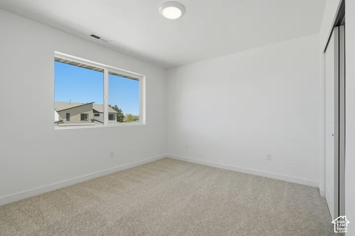 Carpeted room featuring a large window, white walls, and a flush-mount ceiling light