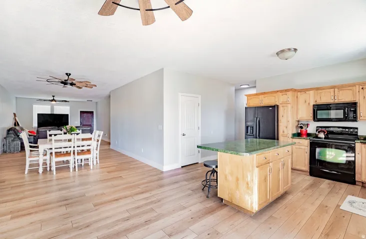 Open-concept layout with wood-finish flooring, a kitchen island with seating, natural wood cabinetry, and recessed lighting