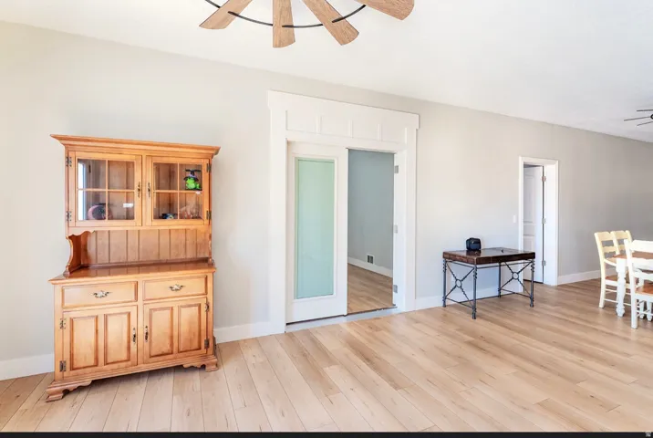 Light wood-finish flooring complemented by white trim and a ceiling fan