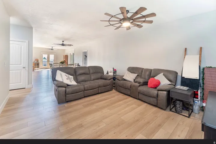 Wood-finish flooring throughout, light-colored walls, ceiling fan with integrated lighting, and a white interior door with panel detailing