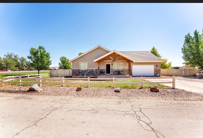 Single-story residence featuring a stone and stucco exterior, an attached garage, a covered front porch with exposed wood beams, and a gravel front yard