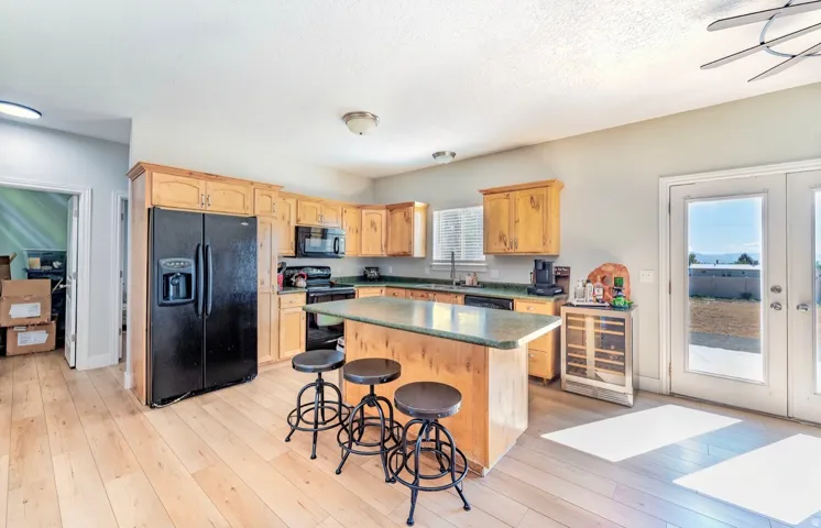 Kitchen featuring light wood-finish flooring, a central island with a countertop, wood cabinetry, and a full-size black refrigerator