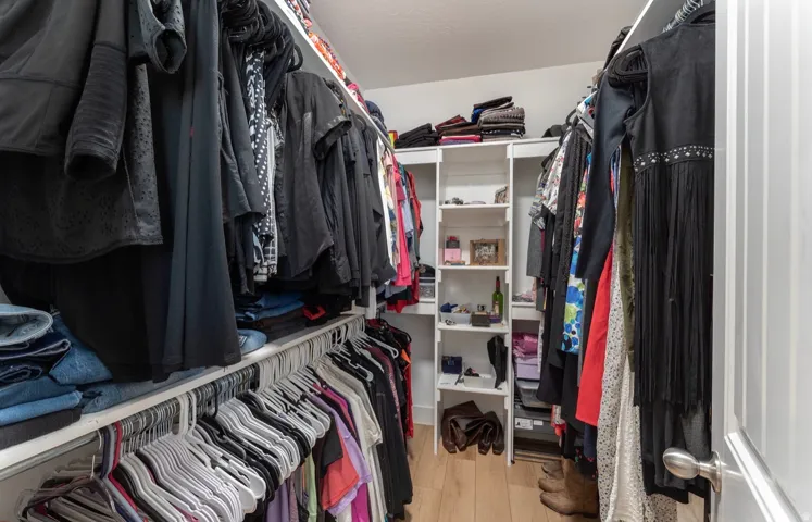 Walk-in closet with multiple hanging rods, integrated shelving, and wood-finish flooring