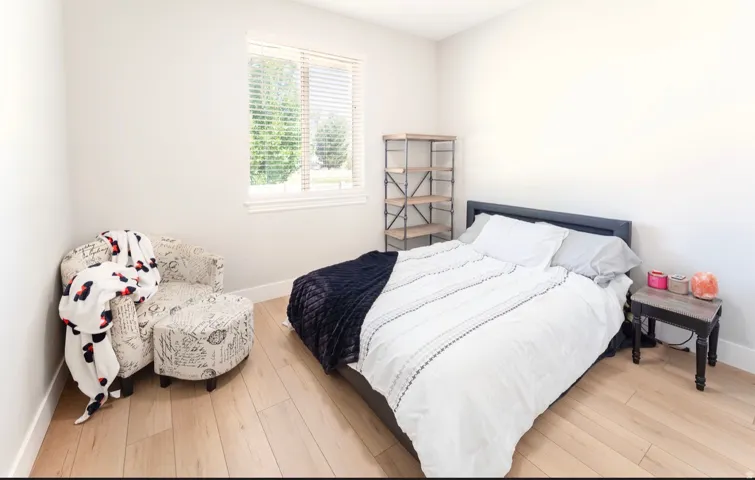 Light-toned wood-finish flooring, white walls, and a window with horizontal blinds