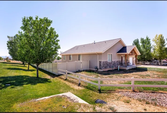 Stucco exterior with stone accenting, covered porch with natural wood pillars, and an attached garage