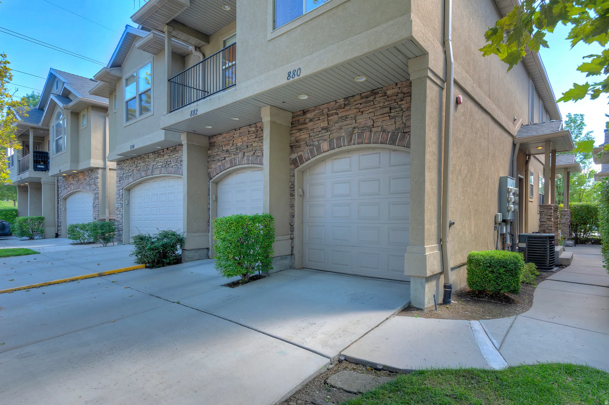 Stucco exterior with stone accents and arched garage doors