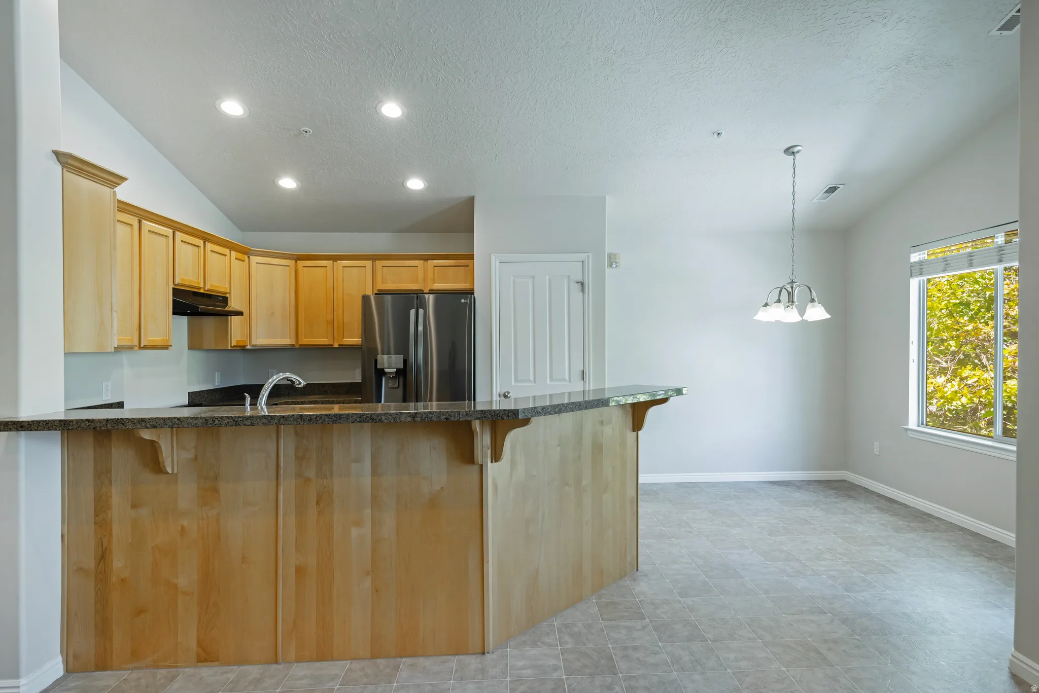 Kitchen with light wood cabinetry, stainless steel appliances, and a breakfast bar
