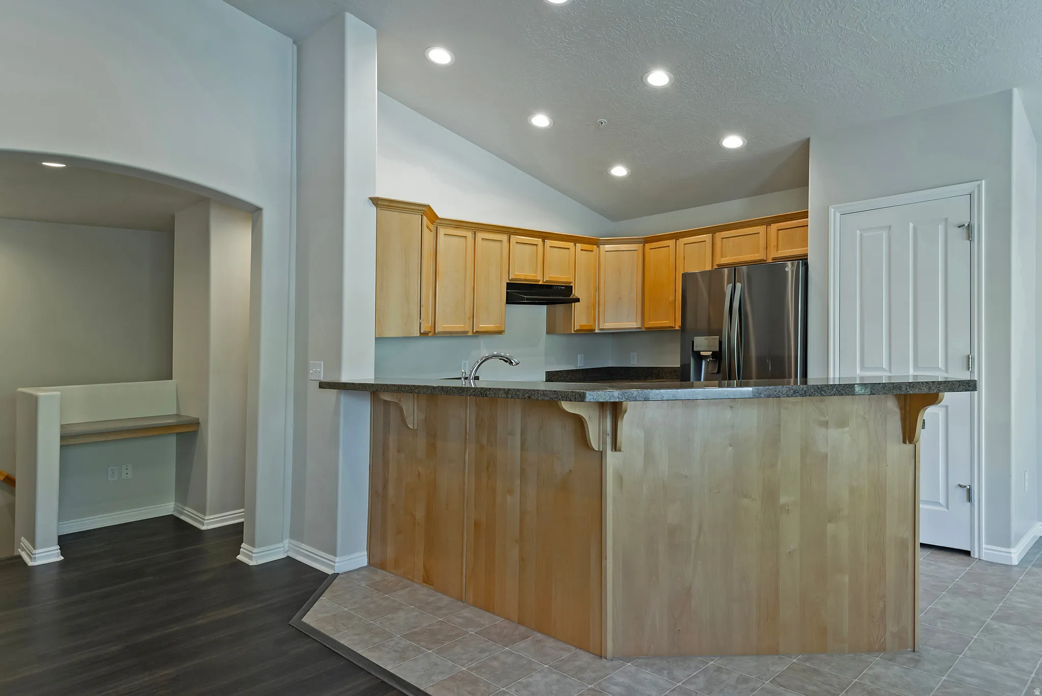 Kitchen featuring light wood cabinetry, stainless steel refrigerator, and recessed lighting