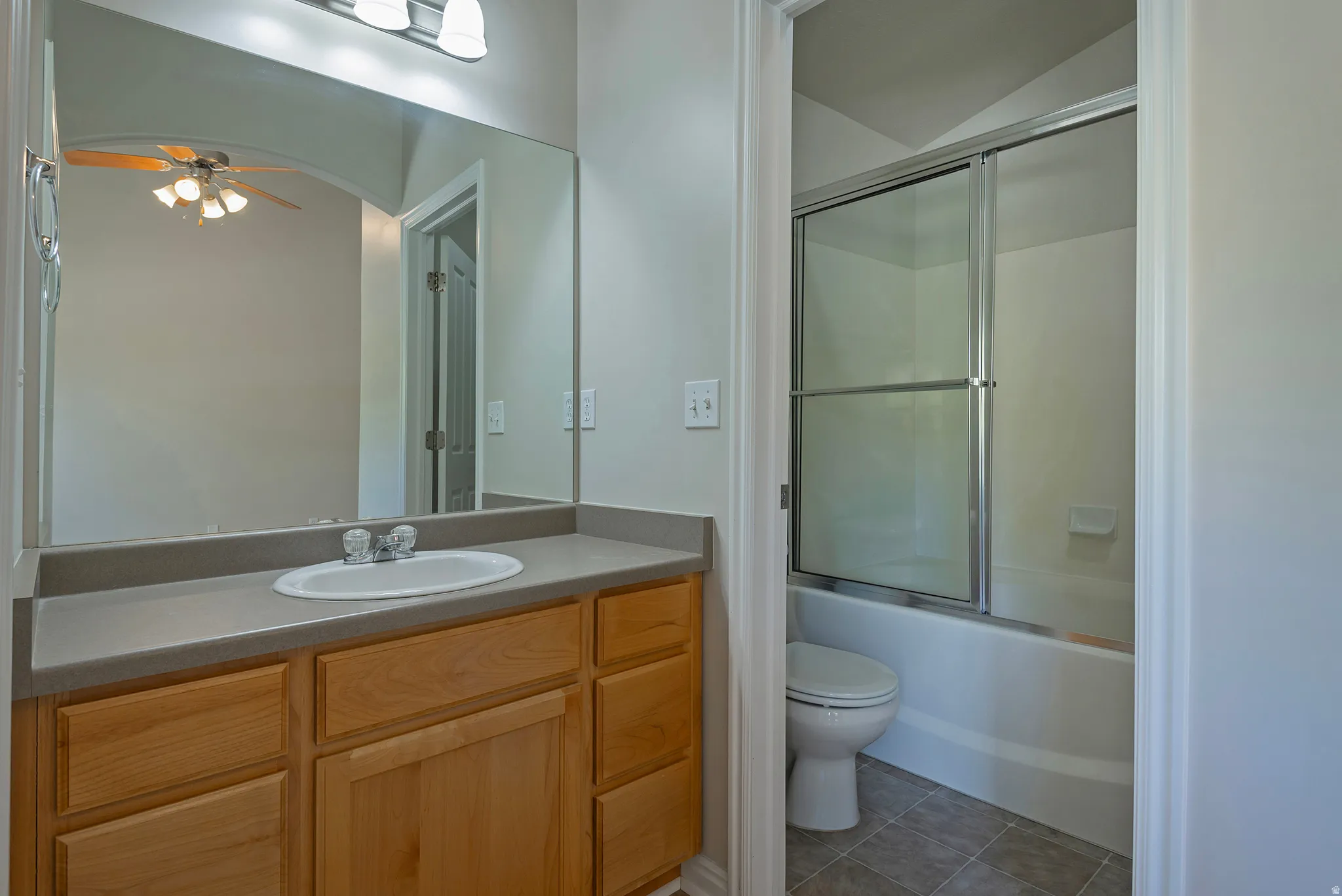 Wood-finish vanity with a single basin sink, laminate countertop, and full-width mirror