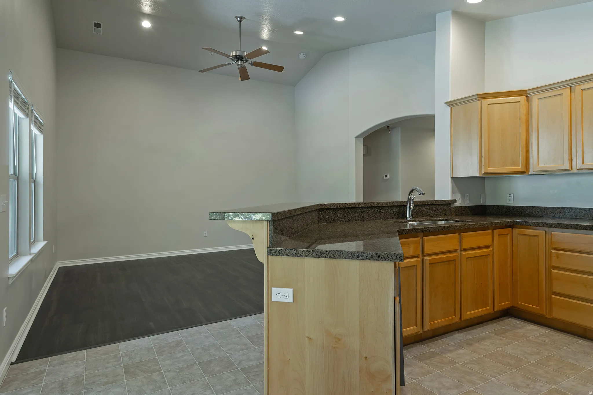 Kitchen featuring wood-finish cabinetry, dark countertops, and a stainless steel sink with a high-arc faucet