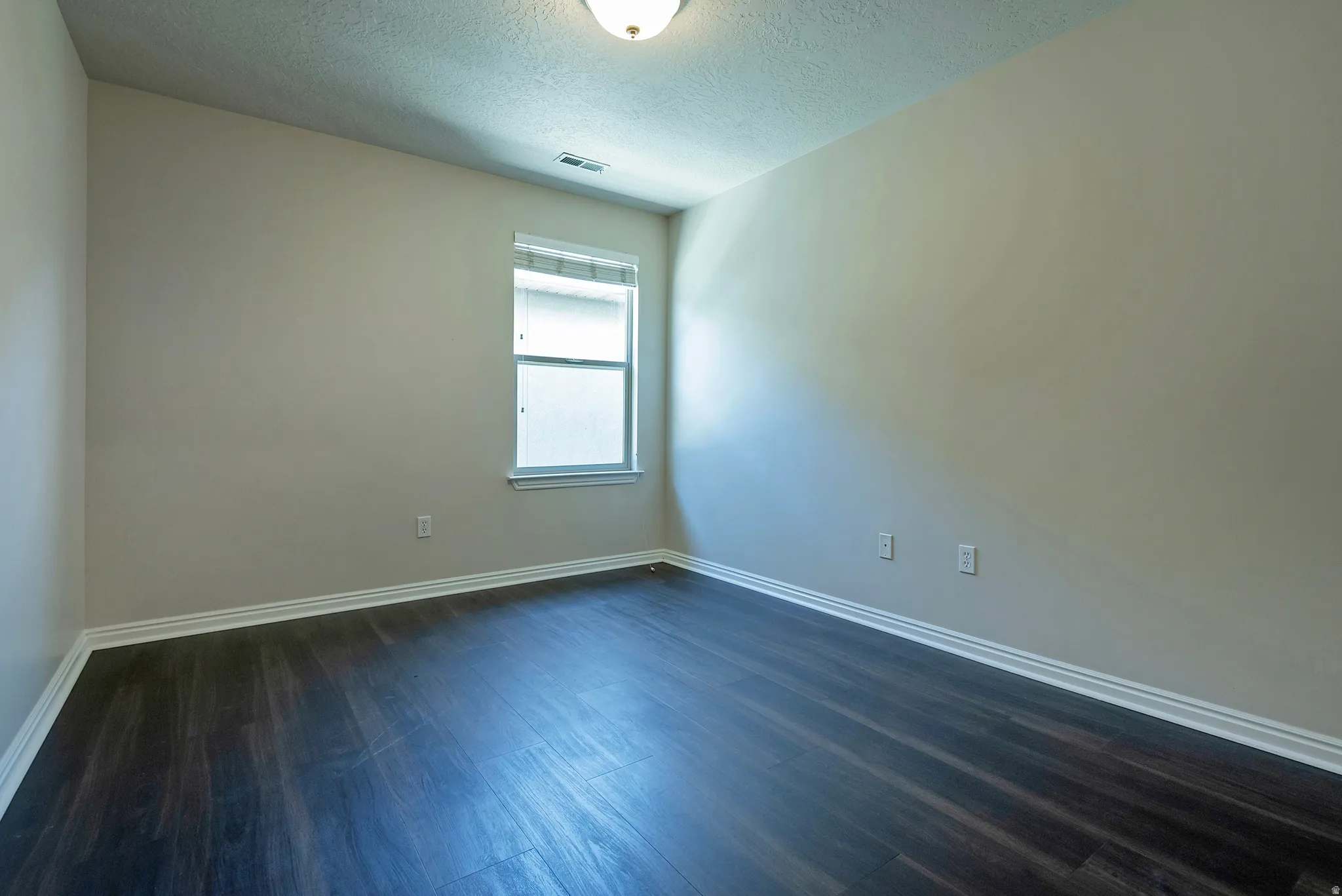 Recessed window with white trim, dark wood-finish flooring, white wall molding, and neutral wall paint