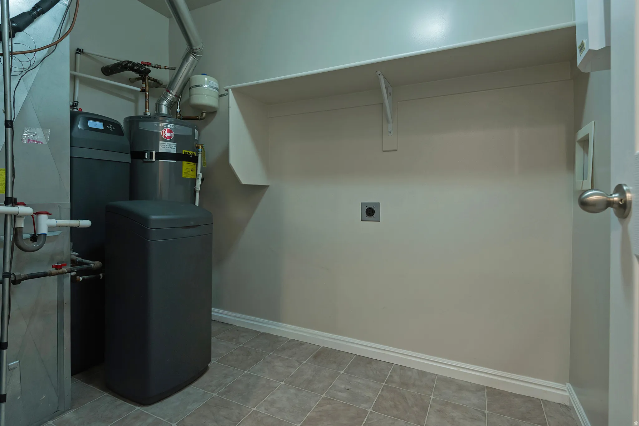 Utility room with durable tile flooring and a built-in shelf