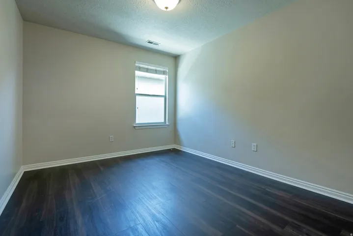 Recessed window with white trim, dark wood-finish flooring, white wall molding, and neutral wall paint