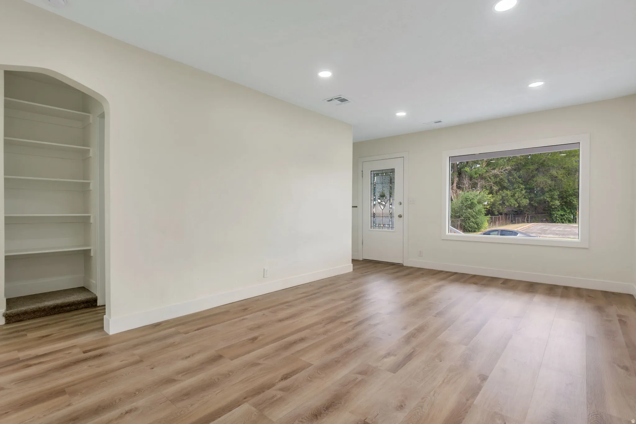 LVP flooring, recessed lighting, and a built-in arched alcove with shelving