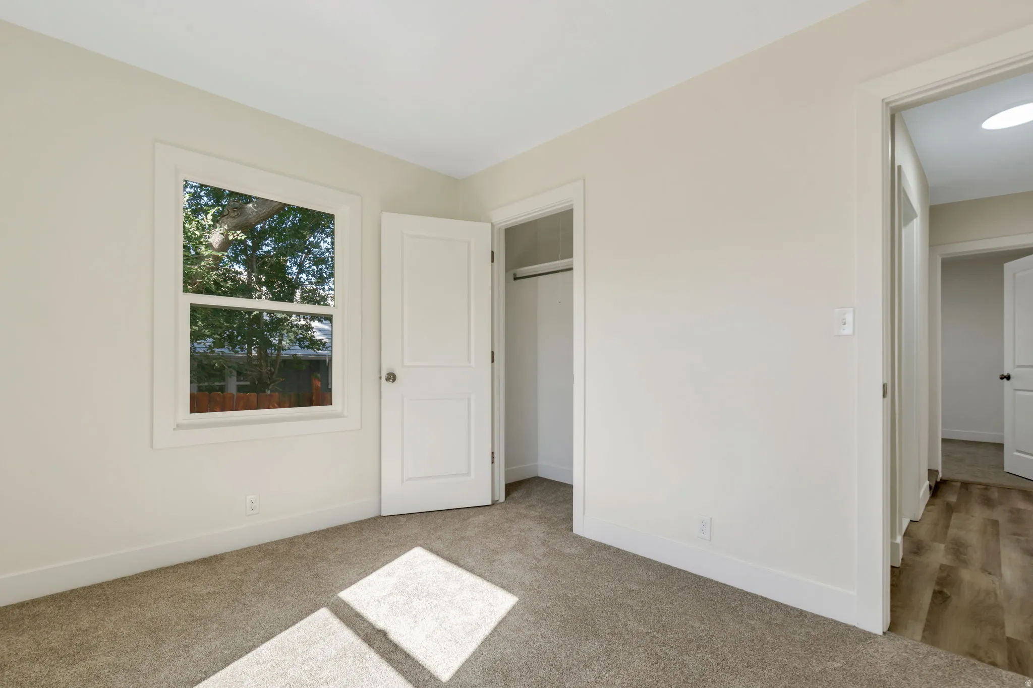 Bedroom 2 - Carpeted flooring, white trim, and a window with exterior views