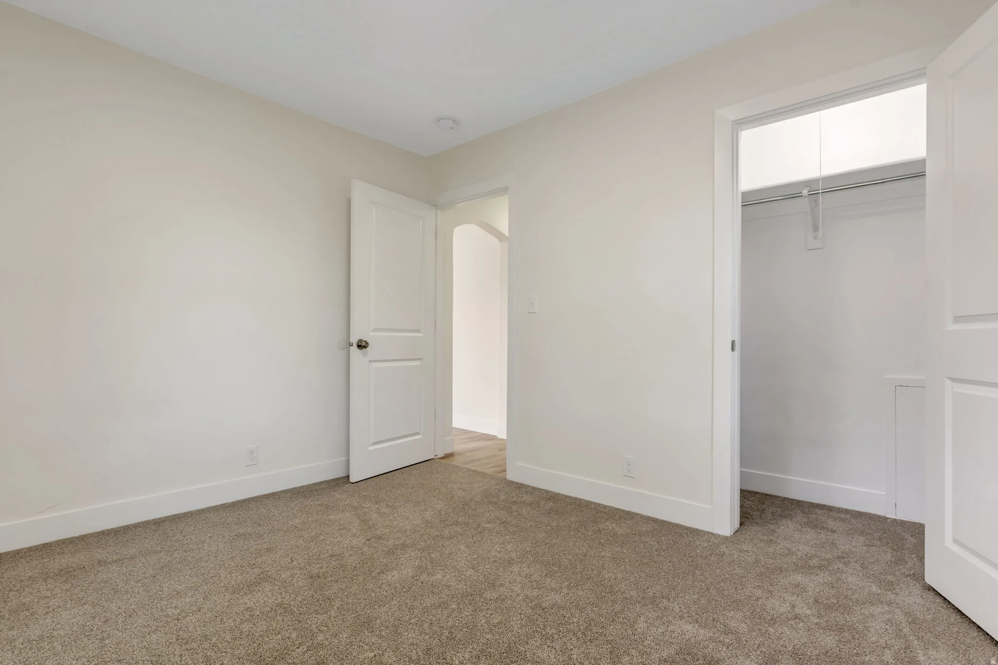 Bedroom 1 - .Light-toned wall finishes, neutral carpeting, white trim, and a built-in closet with hanging rod