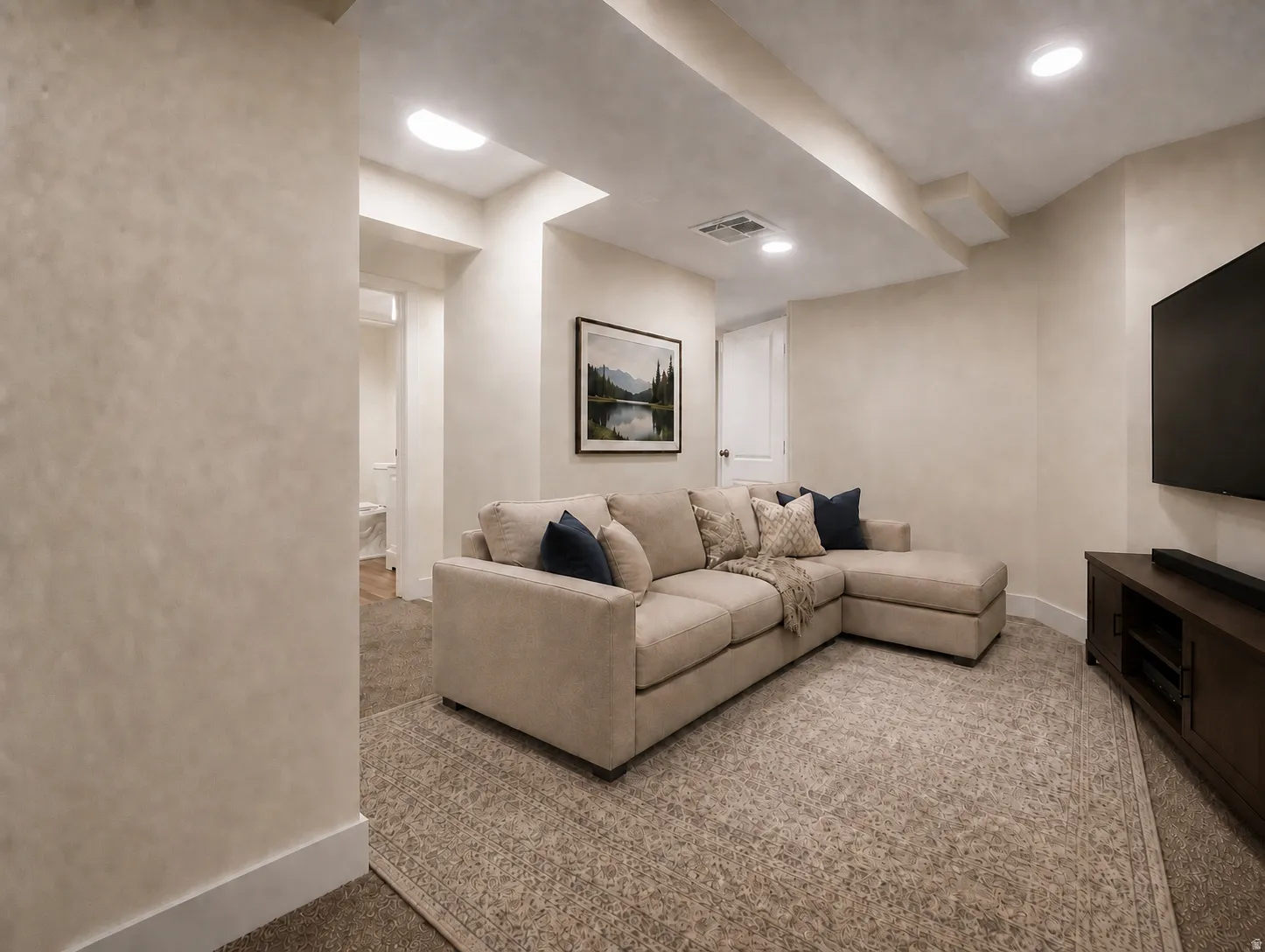Recessed lighting illuminates a carpeted living space with textured walls