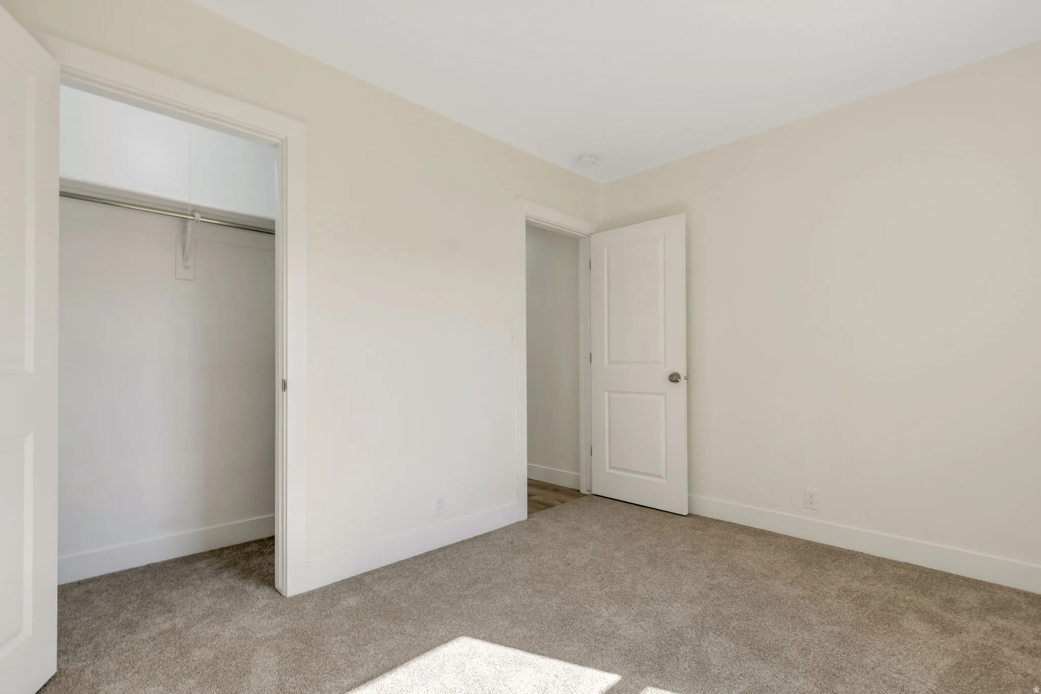 Bedroom 2 - Neutral-toned walls, carpet flooring, recessed ceiling lighting, and a closet with a built-in hanging rod