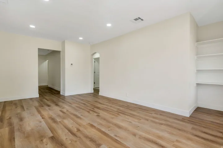 Recessed lighting, LVP flooring, built-in shelving, and an arched doorway