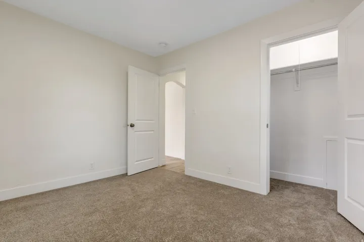 Bedroom 1 - .Light-toned wall finishes, neutral carpeting, white trim, and a built-in closet with hanging rod
