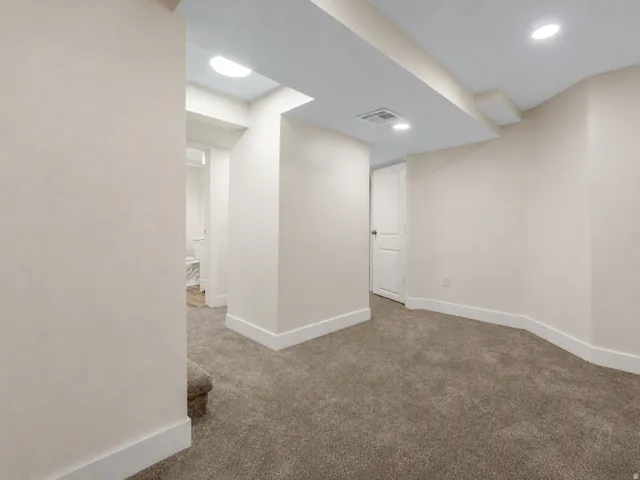 Recessed lighting illuminates the carpeted flooring and light-toned walls, enhancing the neutral interior