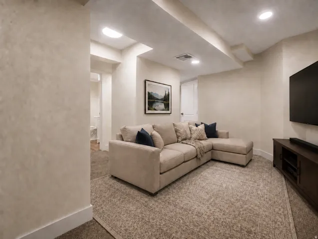 Recessed lighting illuminates a carpeted living space with textured walls