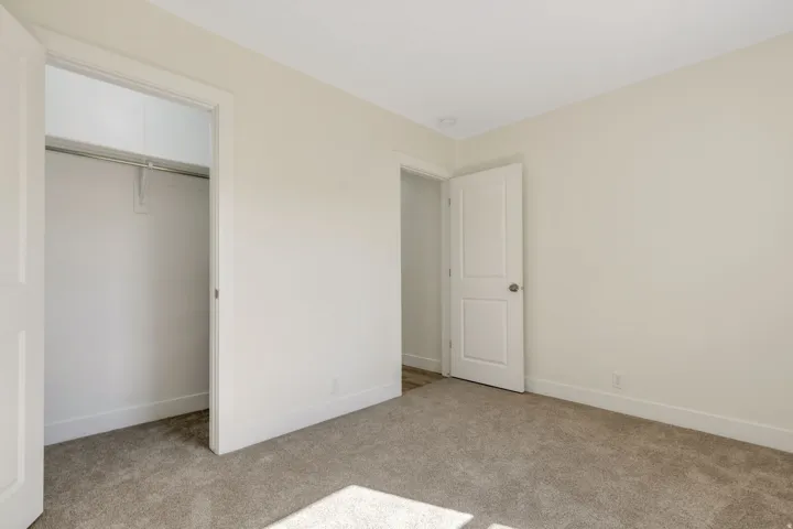 Bedroom 2 - Neutral-toned walls, carpet flooring, recessed ceiling lighting, and a closet with a built-in hanging rod