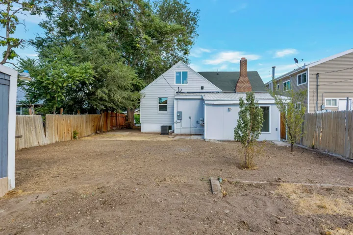 Expansive yard space with a wood privacy fence, a detached shed, and a rear house exterior featuring a brick chimney and vinyl siding