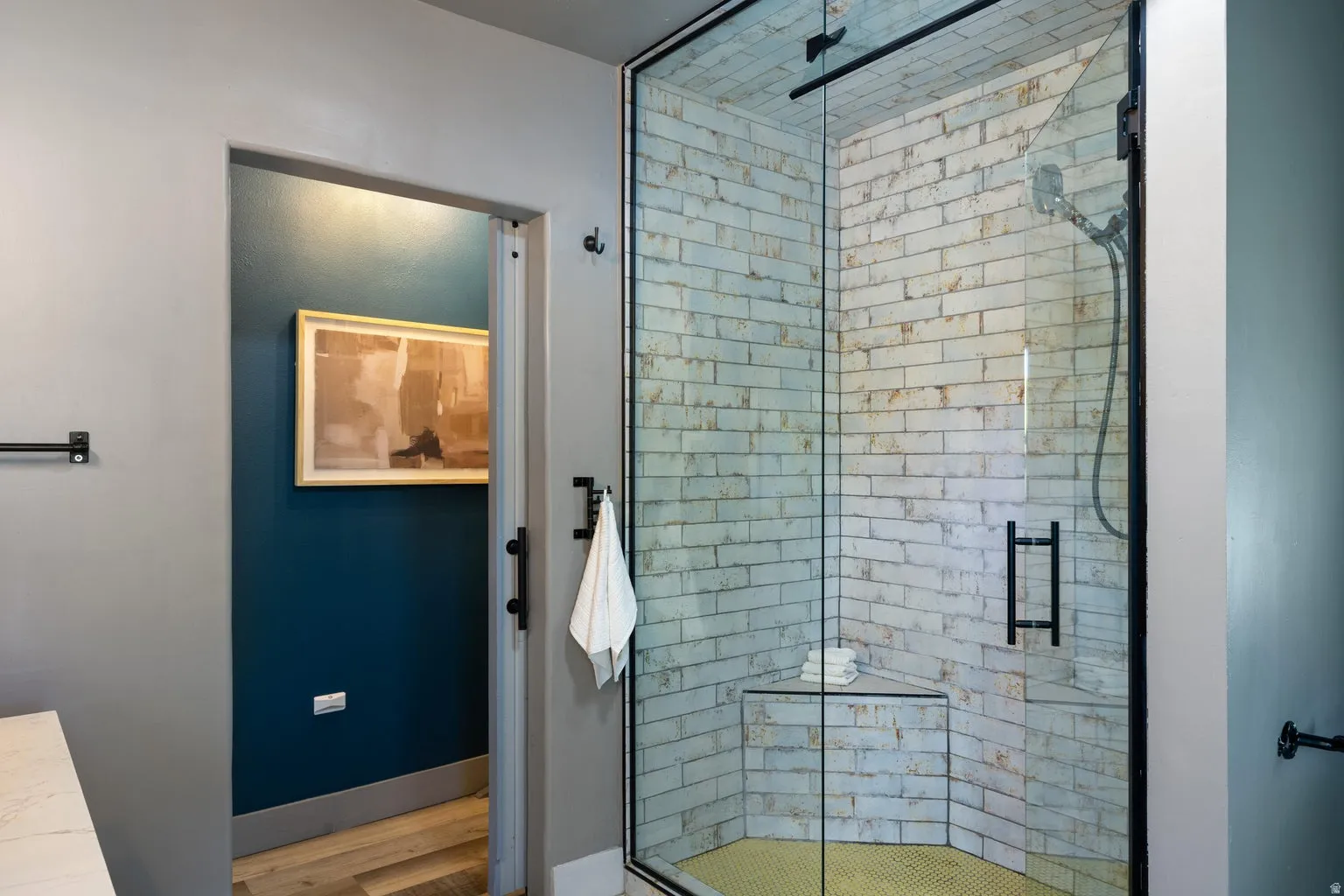 Glass-enclosed shower with subway tile walls and corner bench