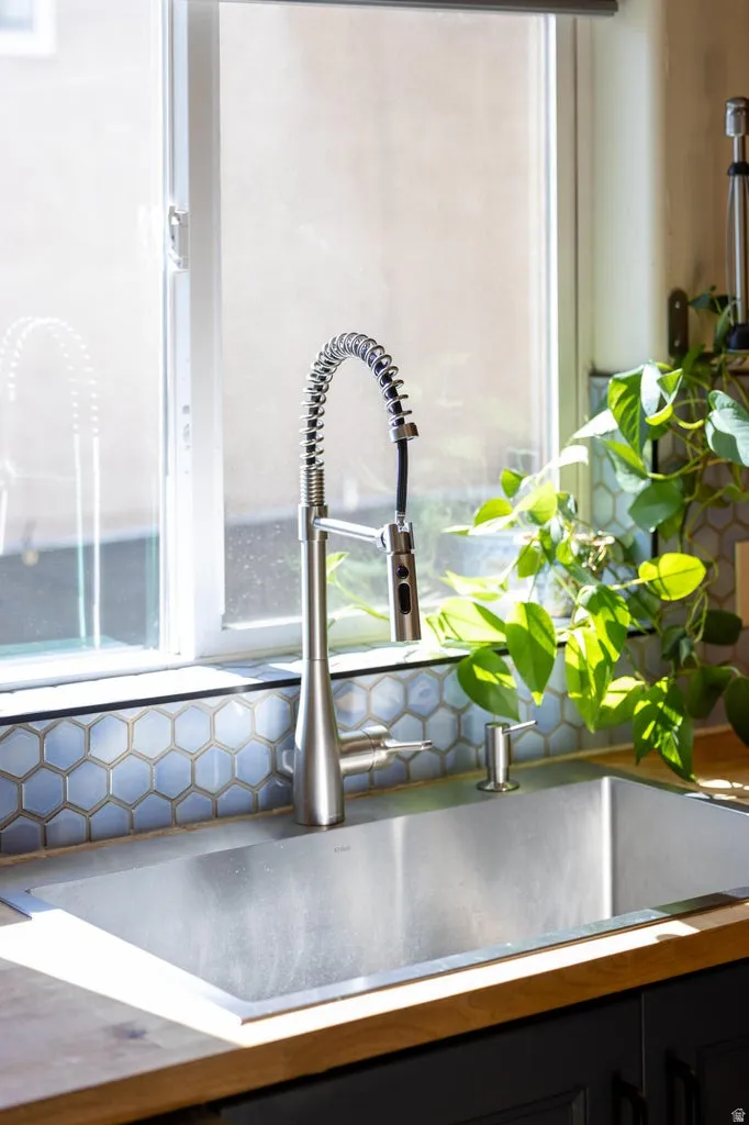 Stainless steel undermount sink with a brushed nickel pulldown faucet, set into wood-finish countertops, complemented by a hexagonal tile backsplash