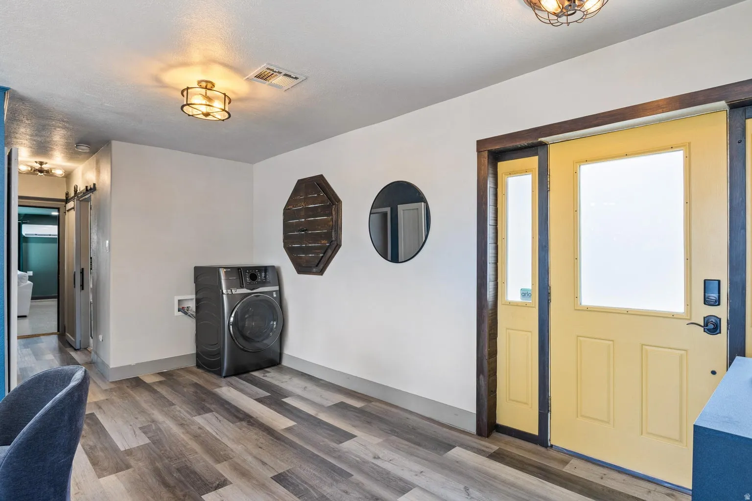 Wood-finish flooring throughout, featuring a yellow entry door with a frosted glass panel, and a coordinated sidelight